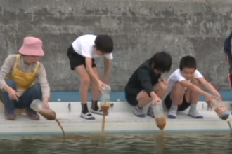関川小学校の児童が　EM発酵液を　プールに投入